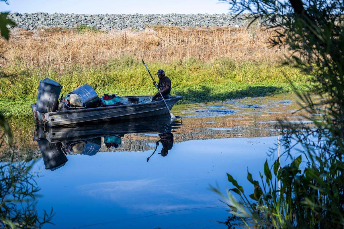 A homeless man moves some of his belonging with a boat on Morrison Creek in south Sacramento on Oct. 6 before the Department of Utilities demolishes his former camp to begin levee work.