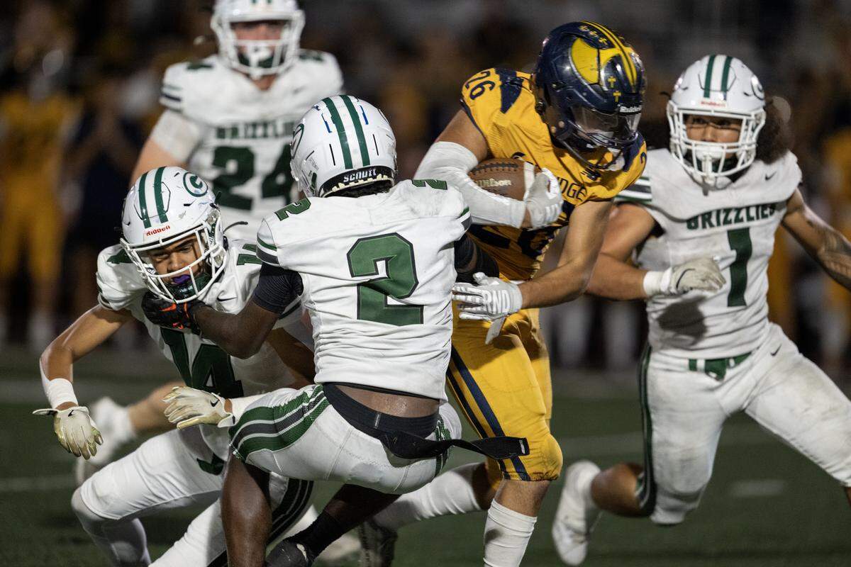 The Oak Ridge Trojans' Tyler Andujar (26) runs past the Granite Bay Grizzlies' Darnell Turner (2) in the second half Friday in El Dorado Hills.
