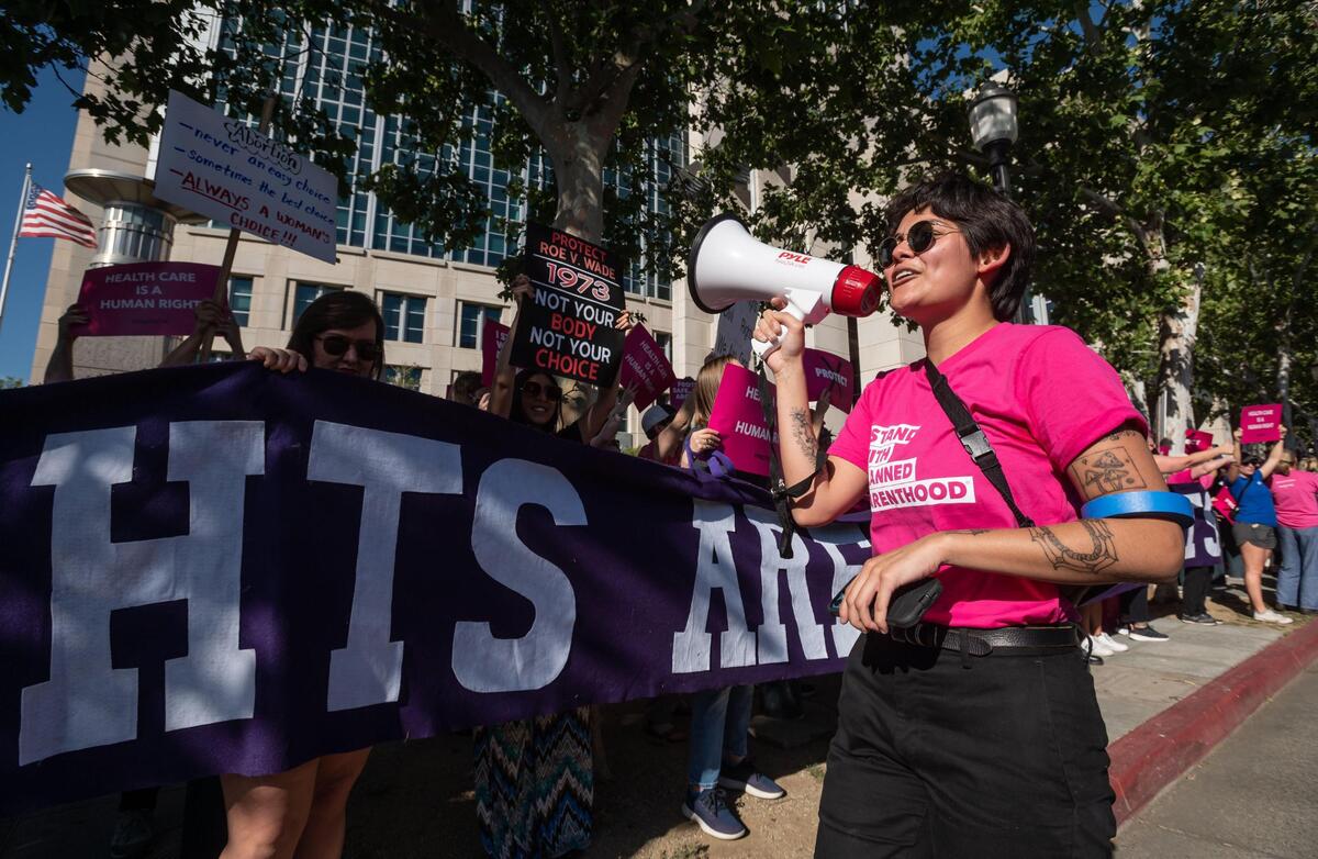Xenia Vidal, with Planned Parenthood Affiliates of California, leads a chant while walking past a line of protesters gathered outside the federal courthouse in downtown Sacramento on Tuesday.