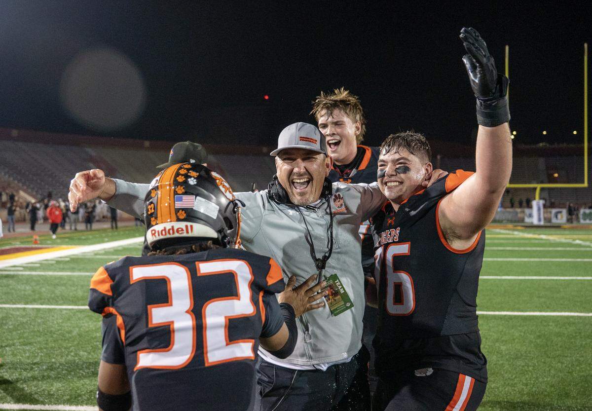 Roseville Tigers coach Adam Reinking celebrates with Caleb Barba (76) and Trejon Jacox (32) following the 31-29 victory over the East Union Lancers the CIF Sac-Joaquin Section football Division lV championship on Saturday at Hughes Stadium in Sacramento.