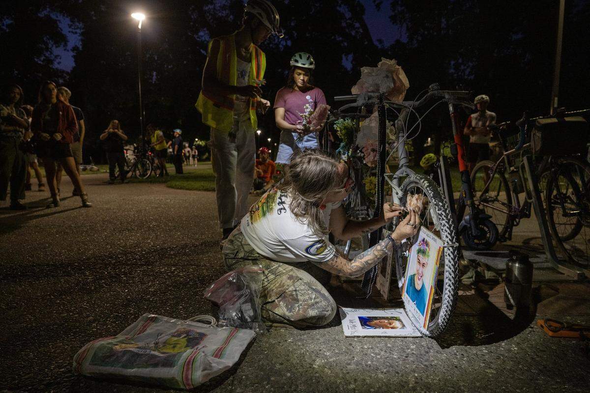 Rucha Powers, whose son Lincoln Sabini was killed while bicycling at UC Davis, leaves photographs of her son on a ghost bike left near Mrak Hall, the campus administration building, during a memorial ride on Wednesday.