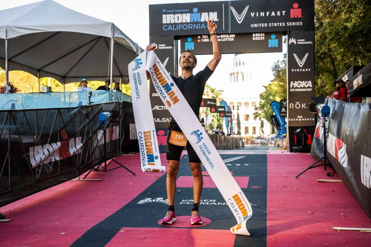 Julien Boulain of Paris, France, points to the sky after finishing in first place in the men’s category of the Ironman California triathlon in Sacramento on Sunday, Oct. 23, 2022.