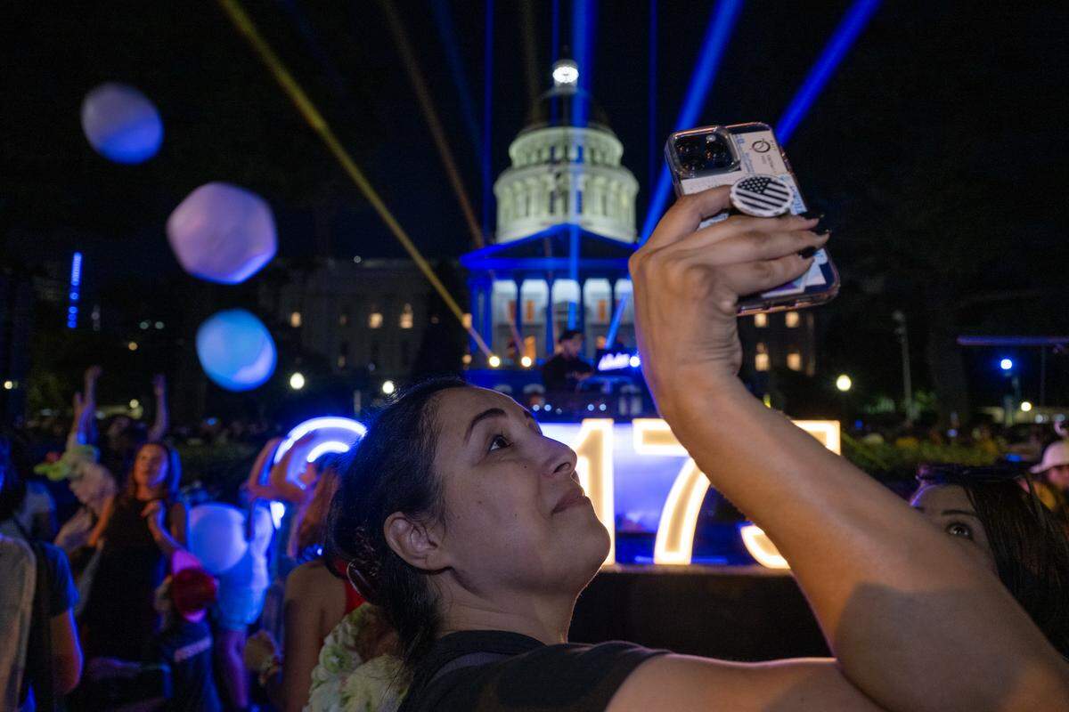 Christina Montano of Sacramento uses her cellphone to makes imagery of a celebration of California’s 175 years of statehood at the state Capitol on Sept. 9, 2025.