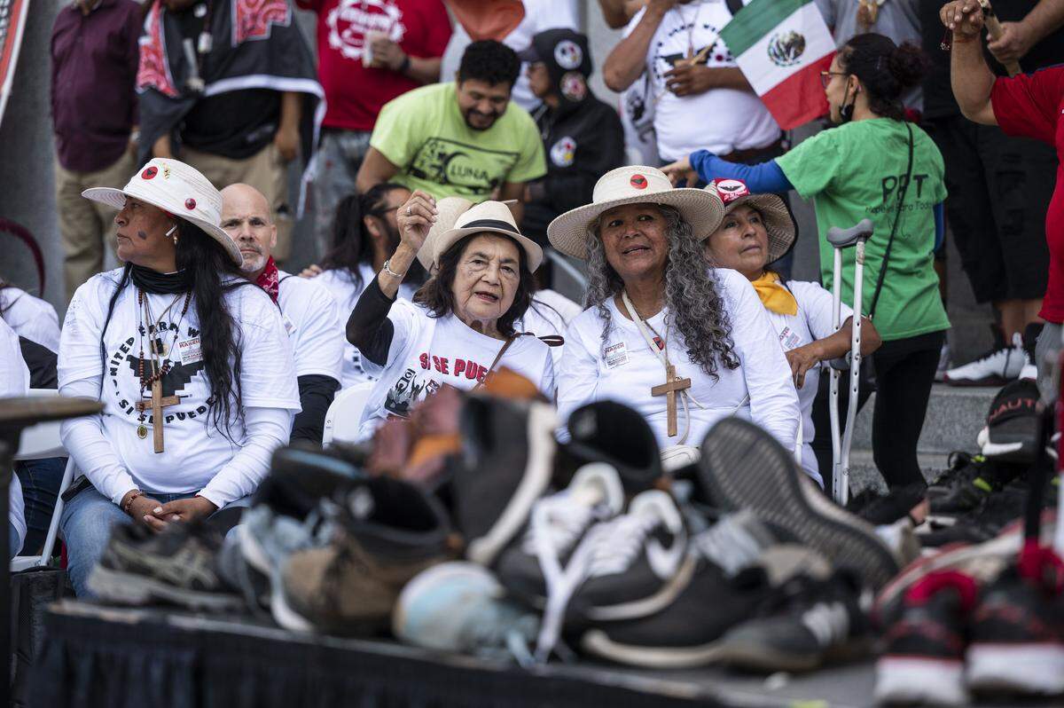 United Farm Workers co-founder and civil rights icon Dolores Huerta talks with UFW president Teresa Romero as the shoes that marchers wore on a 335-mile protest walk from Delano sit on the podium in 2022.