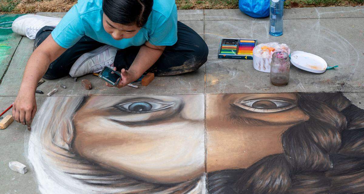 Yixin Huang, 16, a student at St. Francis High School, works on her female empowerment themed artwork during Chalk it Up at Fremont Park on Saturday. Sept. 2, 2023.