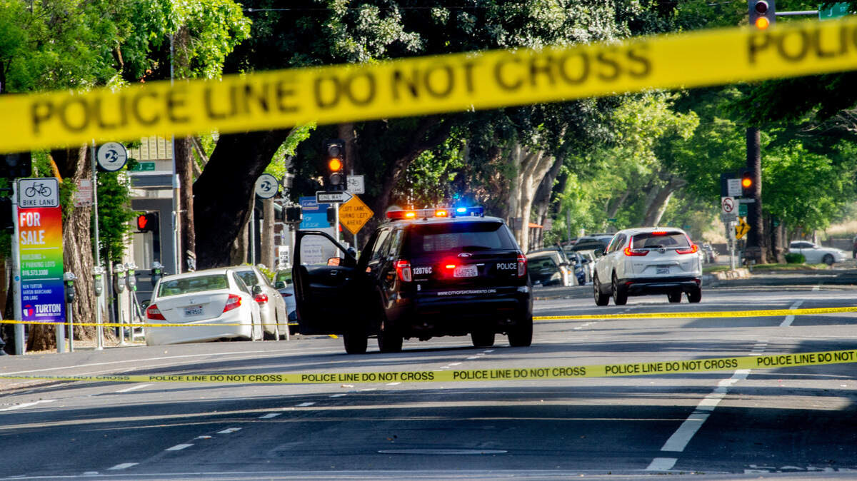 Police tape and a patrol vehicle block 21st Street in midtown Sacramento following a shooting that killed one man and wounded another on Thursday, April 22, 2021.