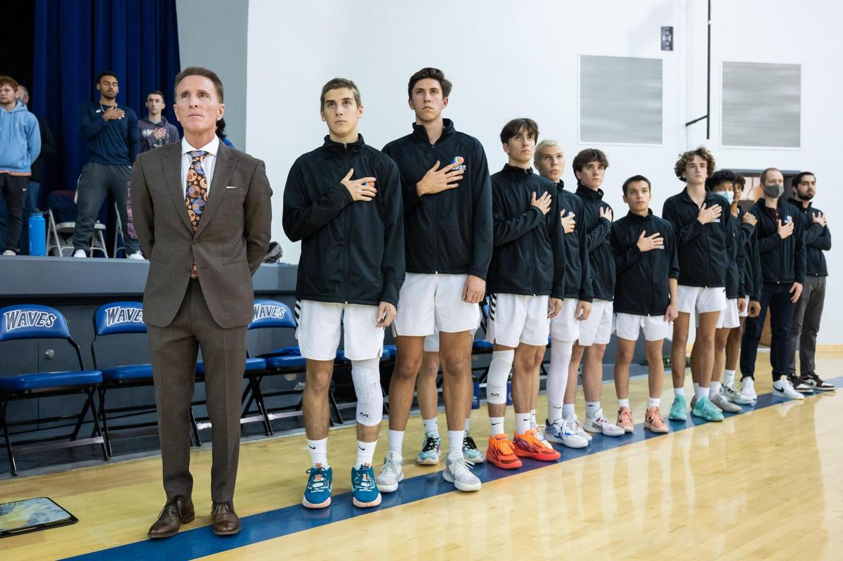 Waldorf Waves coach Dean Stark, dressed in a suit as usual, stands with his team during the national anthem before a game in December at Sacramento Waldorf School in Fair Oaks.