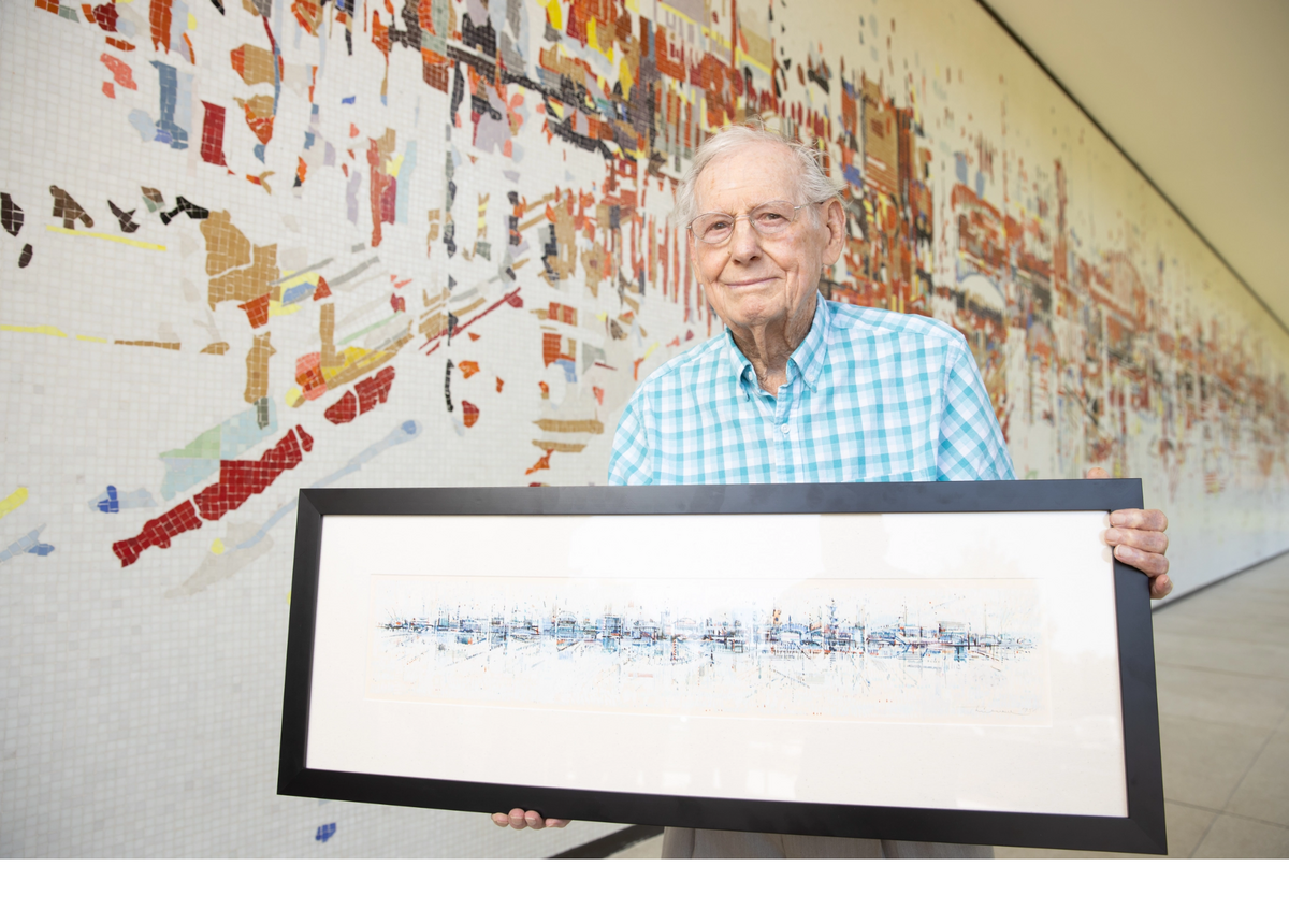 Artist Wayne Thiebaud, who died in 2021, holds a framed image of “Water City,” in front of the actual mural on the old SMUD headquarters building in East Sacramento.