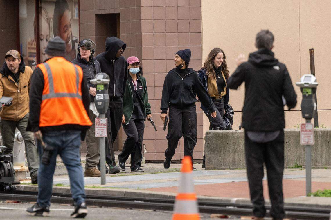 Actors — including Wood Harris, center left, and Regina Hall, center right — take part in the production of “One Battle After Another” in Sacramento in February 2024. The scene recorded included actors running with weapons on 6th Street between I and J streets. 