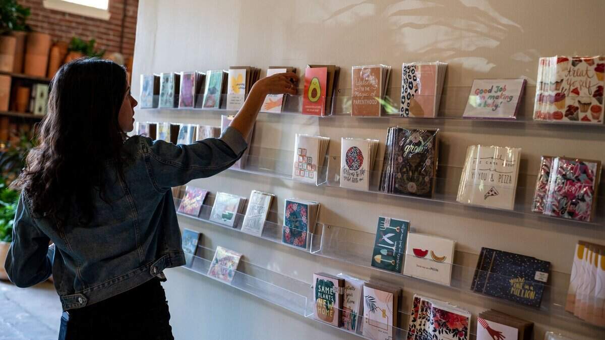 Holly Guzman, who works at Propagate Plants & Gatherings in midtown, arranges Mother’s Day cards on a display Wednesday.