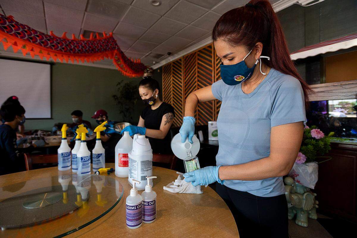 Pho Bac Hao Viet manager Jennifer Tran, right, and Candyce Moua fill sanitizer bottles as they prepare to open the restaurant to customers on Thursday, May 28, 2020 in Sacramento during the coronavirus pandemic.
