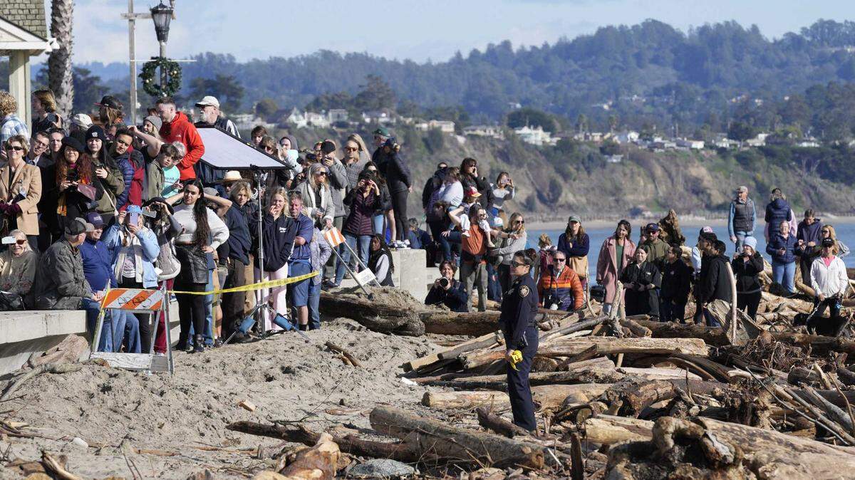 People watch from a distance as President Joe Biden visitsÂ Thursday with business owners and local residentsÂ in CapitolaÂ to survey recovery efforts following a series of severe storms.