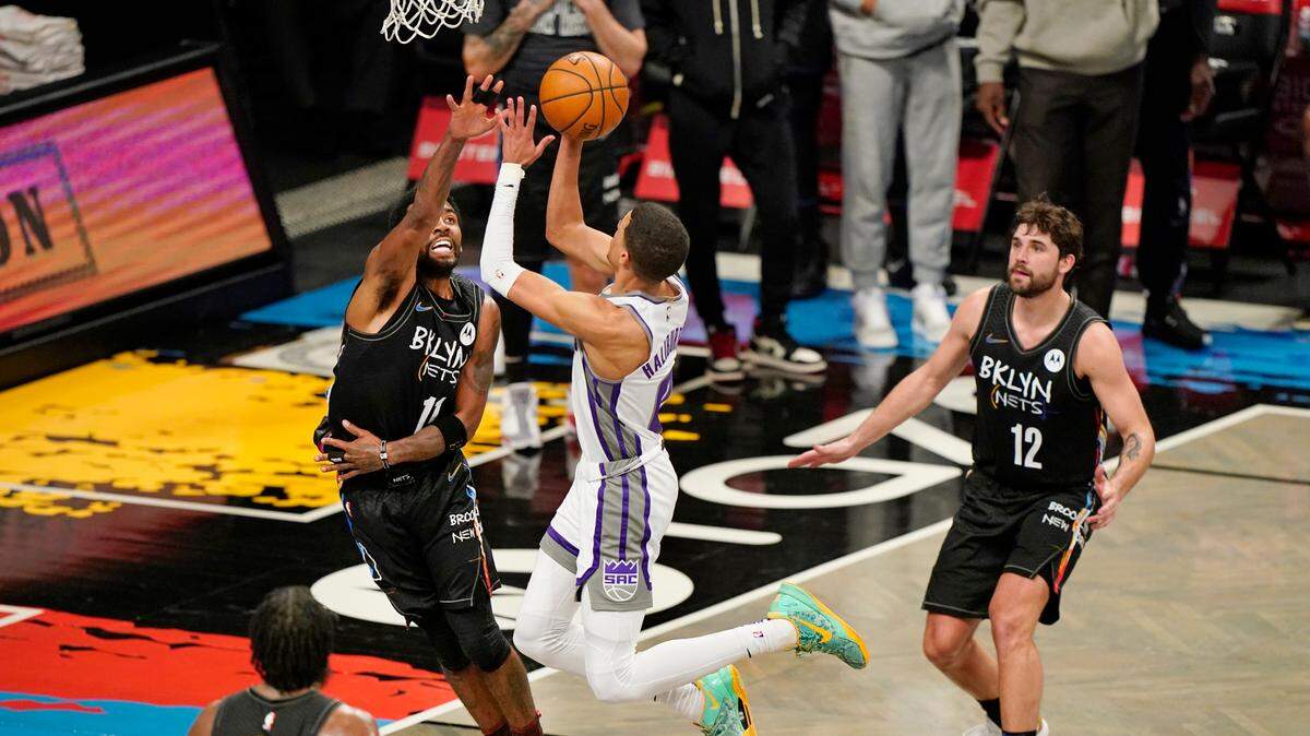 Brooklyn Nets guard Kyrie Irving (11) defends Sacramento Kings guard Tyrese Haliburton (0) as Nets guard James Harden (13) and forward Joe Harris (12) look on from the floor during the fourth quarter of an NBA basketball game, Tuesday, Feb. 23, 2021, in New York. (AP Photo/Kathy Willens)