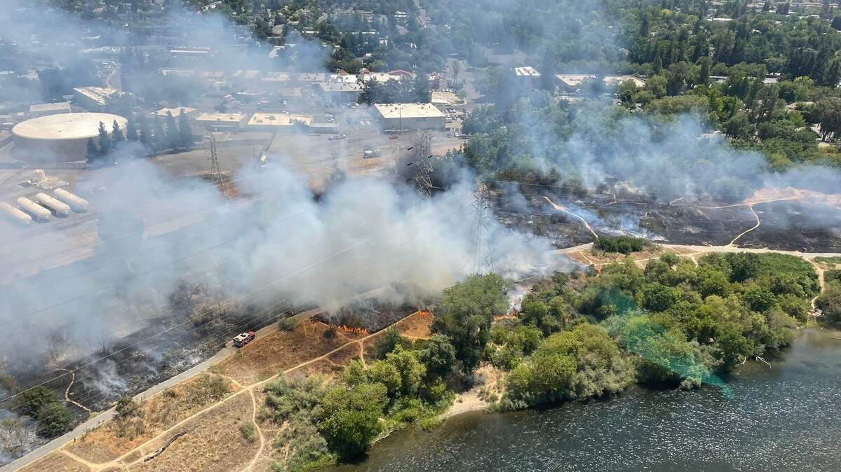 Twenty-two acres of vegetation burn along the American River on June 22, 2022. The fire was under control by midafternoon, Sacramento Metropolian Fire District officials said.