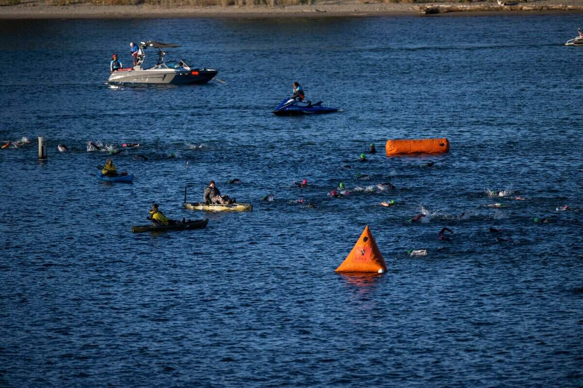 Swimmers in the Ironman California triathlon cross the confluence of the American and Sacramento rivers under the supervision of race monitors on Sunday, Oct. 23, 2022.