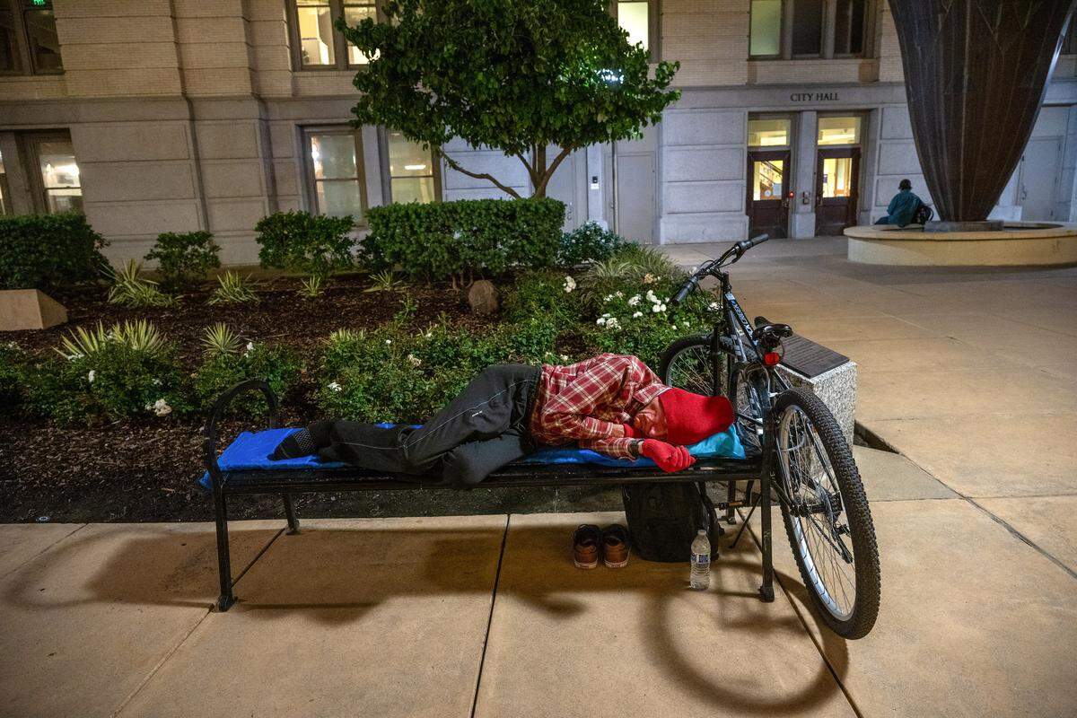 Douglas Grieve, 67, a Navy veteran, sleeps on a bench outside Sacramento City Hall on Wednesday, the last night before an ordinance banning sleeping at the building took effect.
