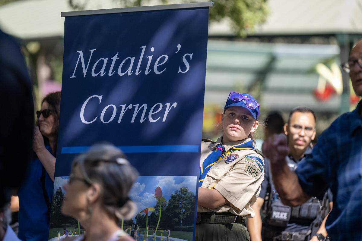 A Girl Scout peers around a banner during a ceremony before the opening of Natalie’s Corner Splash Pad in Davis' Central Park on Saturday. The interactive water feature honors Natalie Corona, the Davis police officer killed in the line of duty in 2019.