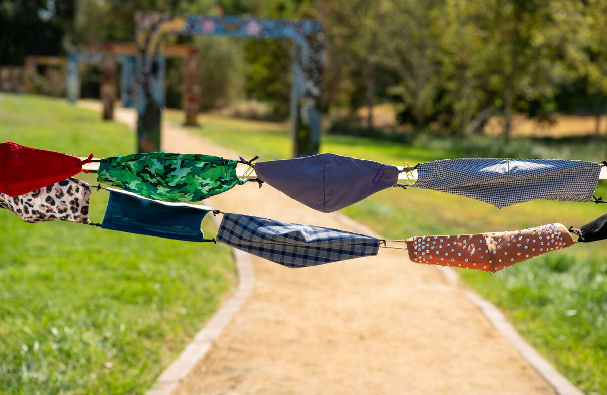 Face masks stitched together are tied to posts for the ribbon-cutting ceremony as the Davis Cemetery District dedicates a permanent COVID-19 Memorial on Sunday.