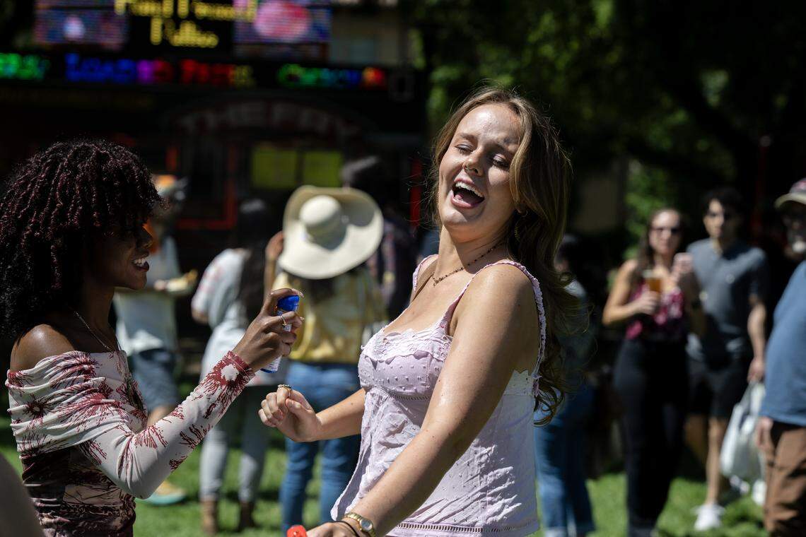 Arielle Jackson sprays sunscreen on her friend Riley Campbell on the UC Davis campus during Picnic Day on Saturday.