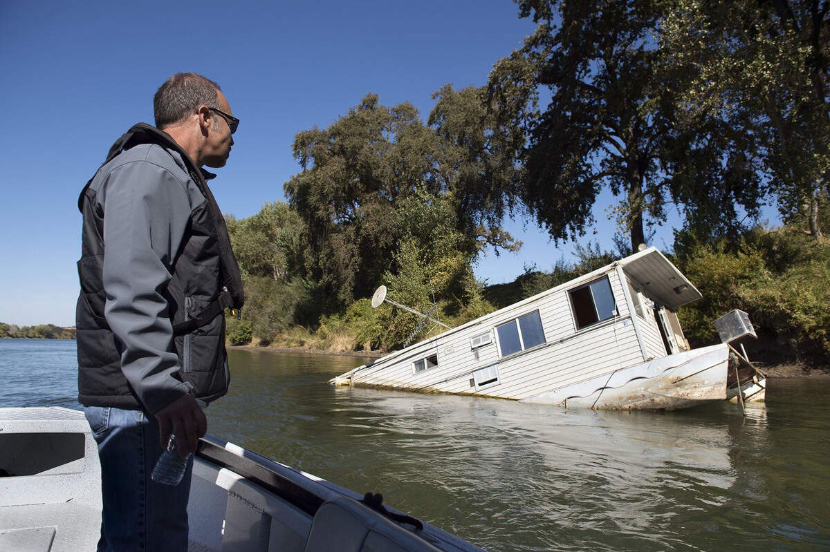 Yolo County Supervisor Oscar Villegas looks at an abandoned houseboat sinking in the Sacramento River south of Interstate 5’s Pioneer Bridge in 2016.