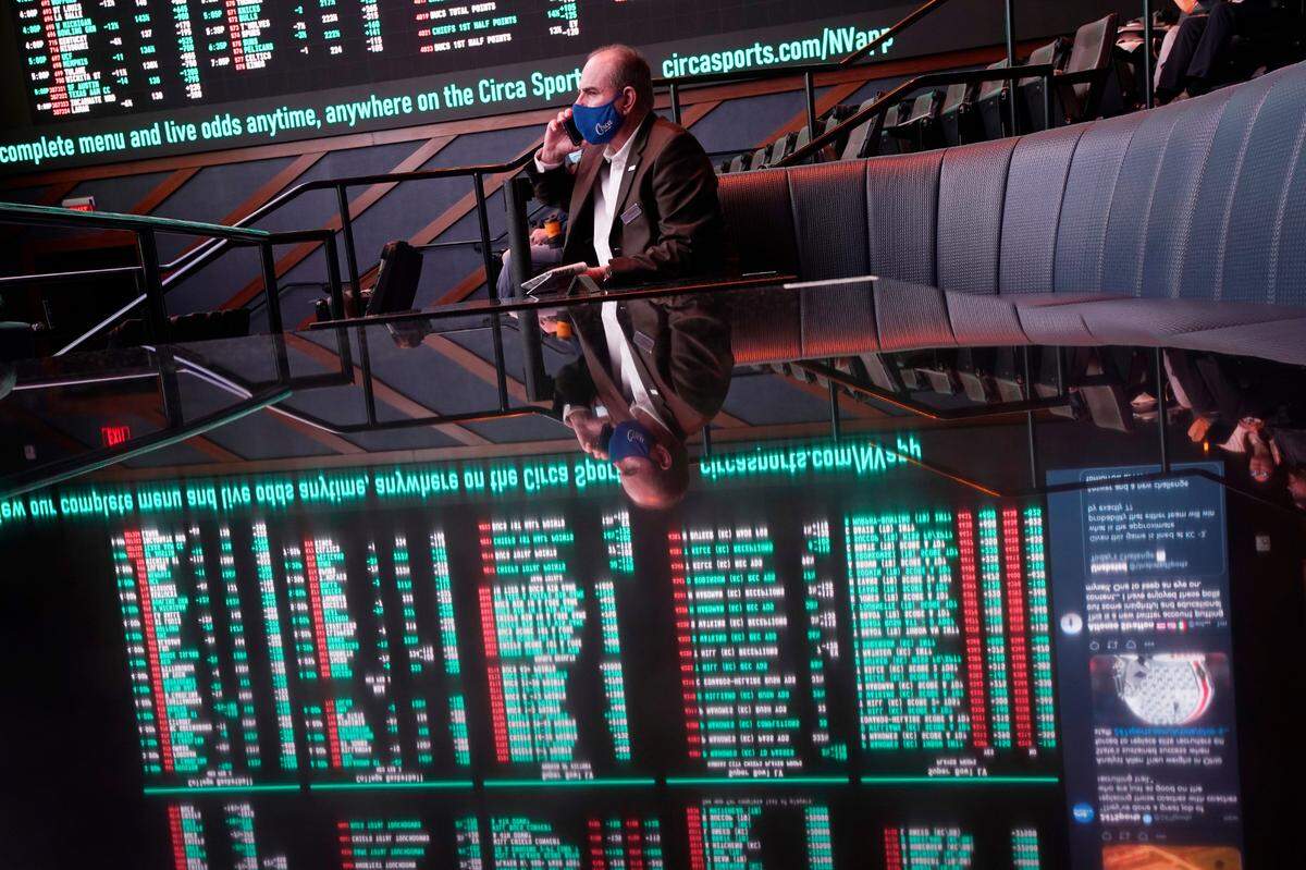 A man sits on a couch as betting odds for the Super Bowl are displayed on monitors at the Circa resort and casino sports book in Las Vegas in February.