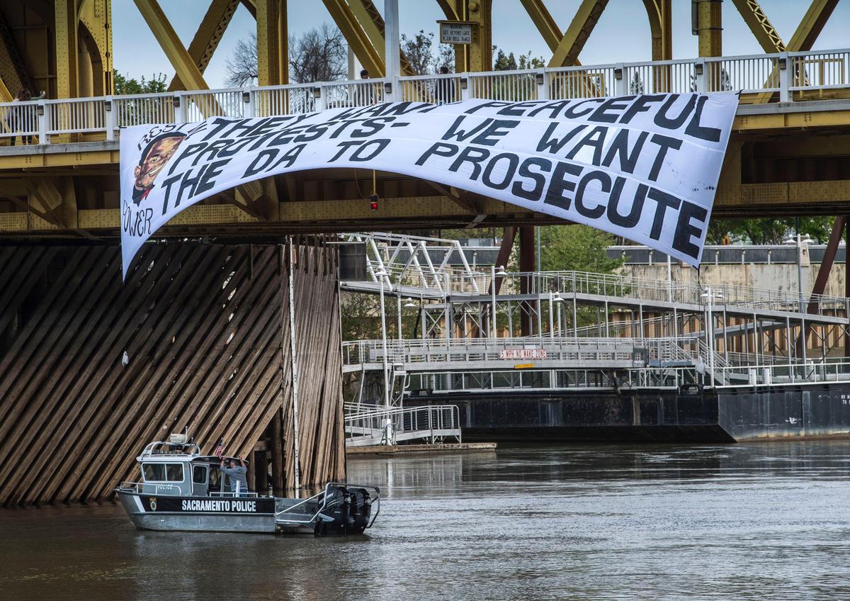 A Sacramento Police boat floats under a banner hung from the Tower Bridge reading, "They want peaceful protests - we want the DA to prosecute." The 75-foot banner went up Wednesday afternoon, several hours after Sacramento County District Attorney Anne Marie Schubert addressed the media and asked for patience in the March 18 police shooting death of Stephon Clark. Sacramento activists Kristina Flores and Aliyah Sidqe took credit for hanging the banner.