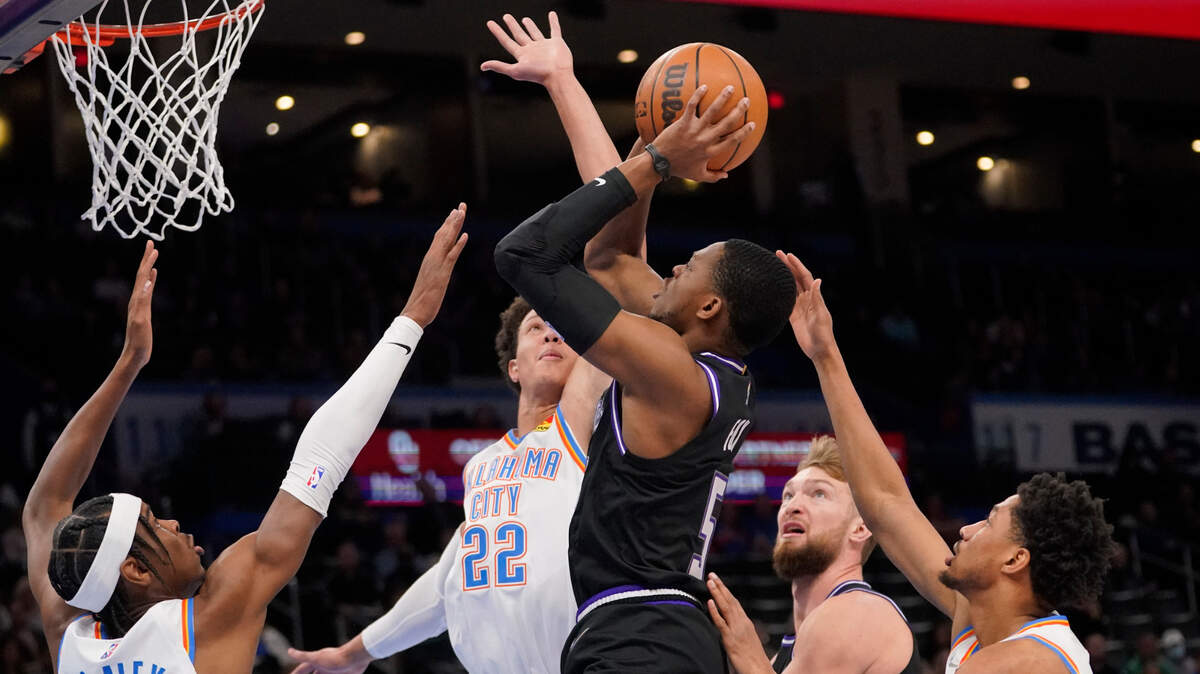 Sacramento Kings guard De’Aaron Fox (5) shoots between Oklahoma City Thunder guard Shai Gilgeous-Alexander (2), forward Isaiah Roby (22) and guard Aaron Wiggins, right, in the first half of an NBA basketball game Monday, Feb. 28, 2022, in Oklahoma City. (AP Photo/Sue Ogrocki)