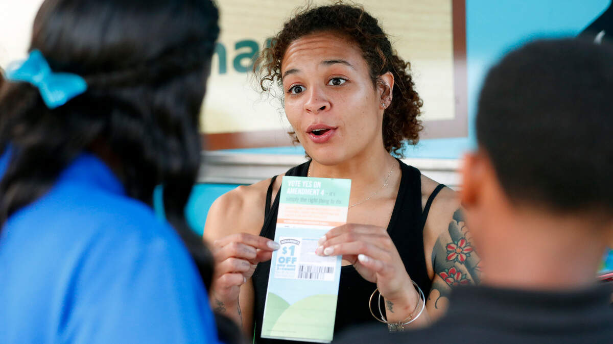 Jessica Jones, center, speaks to people gathered around the Ben & Jerry’s “Yes on 4” Truck about Amendment 4 at Charles Hadley Park in Miami in October.