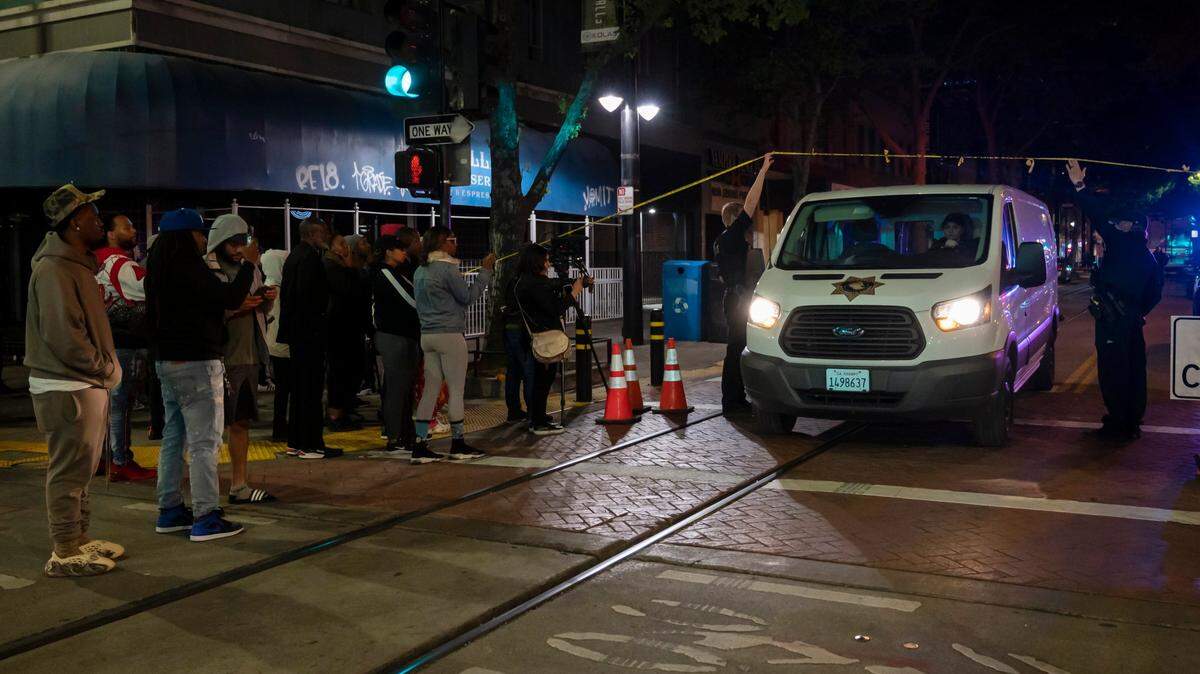 A coroner’s van leaves the mass shooting scene at 9th and K streets after 9 p.m. while community members stand at the corner on Sunday night, April 3, 2022, in downtown Sacramento.