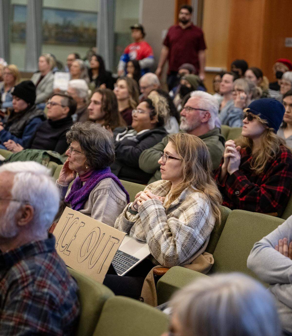 Valerie Love, of Davis, displays a sign opposing ICE as she listens to speakers during the Sacramento City Council meeting on Tuesday.