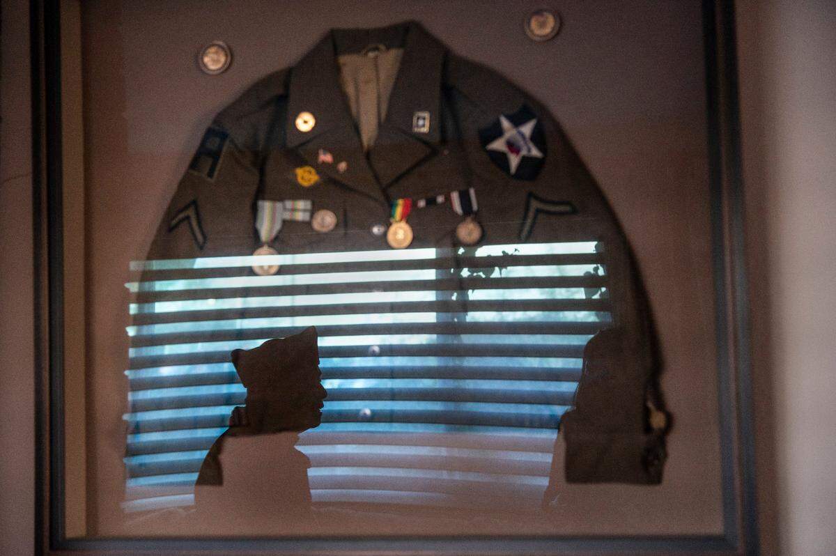 Ken Mar, 95, is reflected in the glass of his framed uniform from 1945 that he wore for official occasions after he fought on the front lines during World War II. “The kids framed it up there for me,” said Mar, who recently received the Congressional Gold Medal, at his Sacramento home on Dec. 7, 2020. He said he was the only Chinese American in his infantry unit.