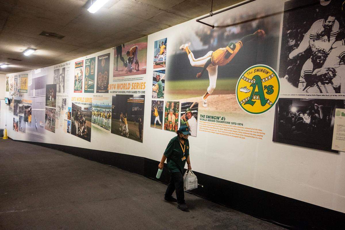 An Oakland Coliseum employee walks past images of historical moments in a back hallway at the coliseum Wednesday, Aug. 21, 2024, before the Athletics play the Tampa Bay Rays.