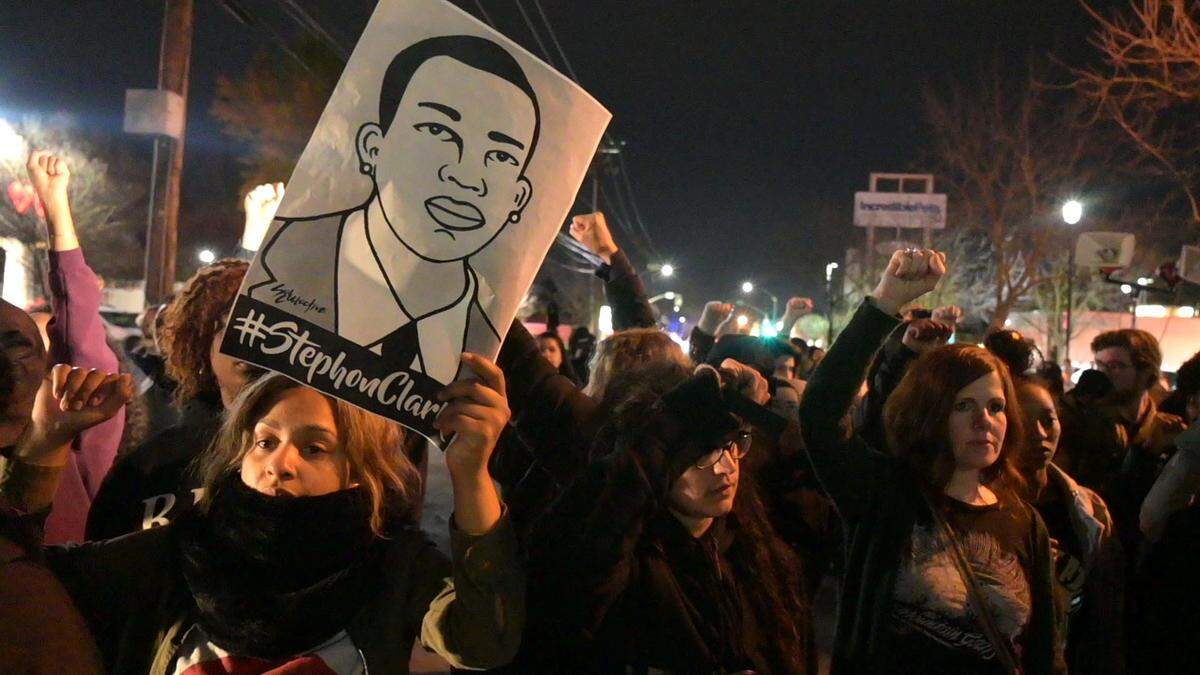 A protester holds up a sign memorializing Stephon Clark during a march Monday protesting the Sacramento County DA’s decision not to charge the officers who shot and killed him.