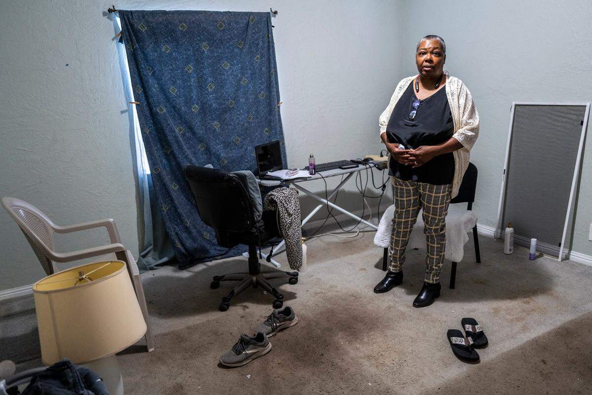 Lenora Jackson uses an ironing board as a desk earlier this month after moving her real desk and other belongings into storage while fighting to stay in her Oak Park rental home. The room was her bedroom until the bedbugs infested her bed and she had to remove it. She says the stained rugs were there when she moved in and need to be replaced.