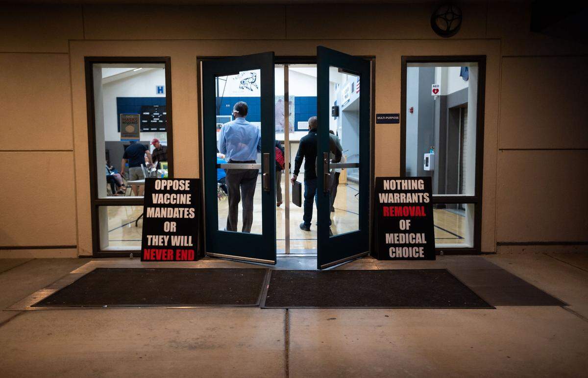 Signs opposing vaccine mandates, left by a group of mothers, greet people entering the Loomis Union School District board meeting in October 2021, at the H. Clarke Powers Elementary School gymnasium in Loomis.