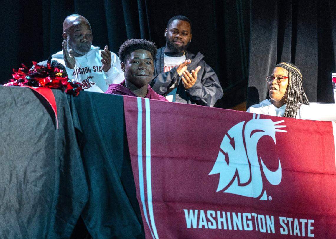 Grant High School running back Wayshawn Parker is celebrated by his family as he prepares to sign with Washington State on Dec. 20 during a National Signing Day event at the high school.