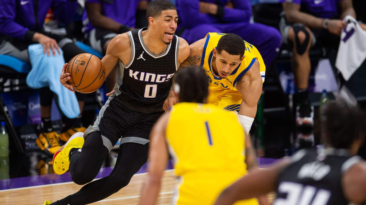 Sacramento Kings guard Tyrese Haliburton (0), left, dribbles around Golden State Warriors forward Juan Toscano-Anderson (95) during the second period of the NBA game Thursday, March 25, 2021, at Golden 1 Center in downtown Sacramento.