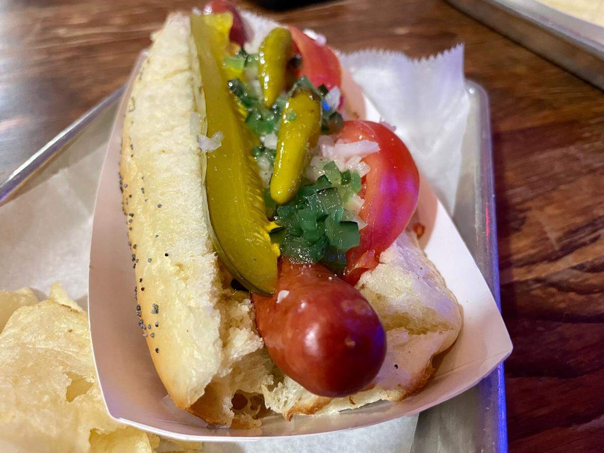 Tomato Alley Free House’s Chicago dog piles onions, sport peppers, tomatoes, relish, mustard and a dill pickle spear between a poppy seed bun.