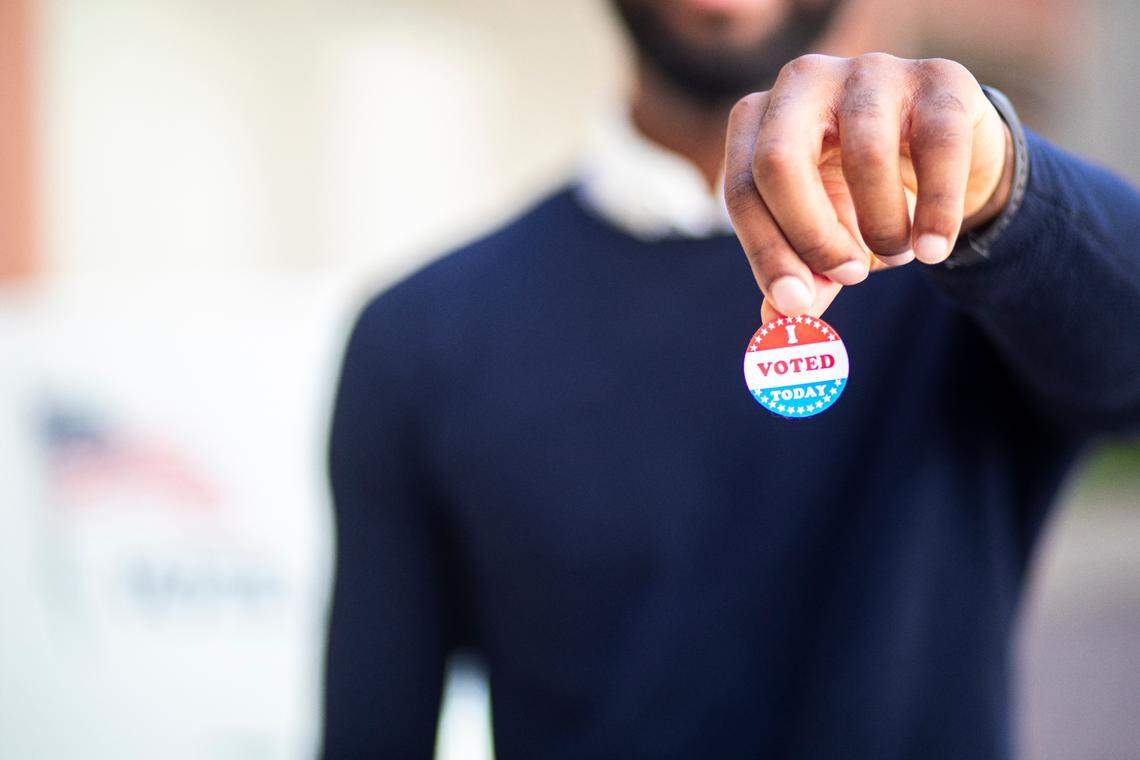 A man holds an "I voted" election sticker in a share image for election endorsements