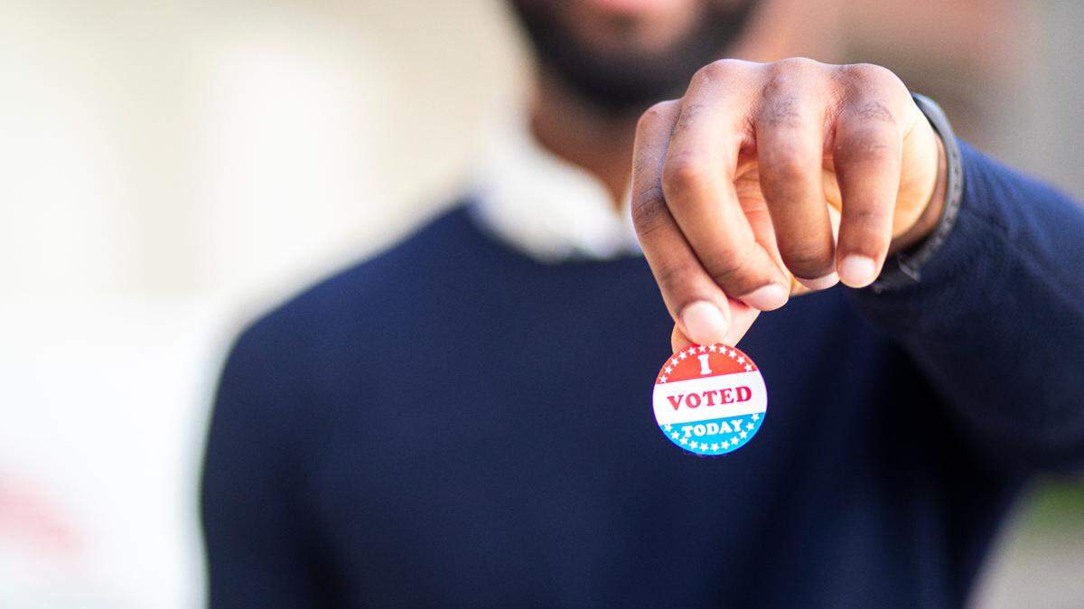 A man holds an "I voted" election sticker in a share image for election endorsements