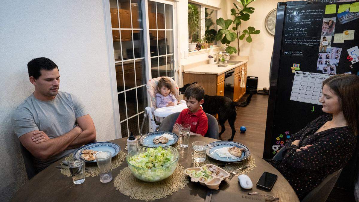 Anna Curry and her husband Issak pray before eating dinner with their children, Lotus, 1½, and Kylan, 6, on Monday, Feb. 3, 2025, in Rancho Cordova. The couple has a 2.25% mortgage rate on their 1,067-square foot property, and has decided to stay in the too-small home rather than give up the favorable rate.