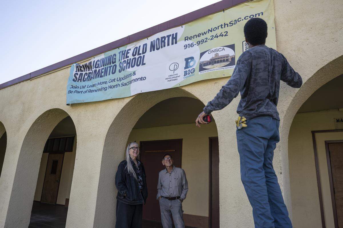 Neighbors Jack Nielsen and Kim Scott, who serve as co-chairs of the Old North Sacramento Restoration Committee, watch as a banner is adjusted outside the Old North Sacramento School on Feb. 2.