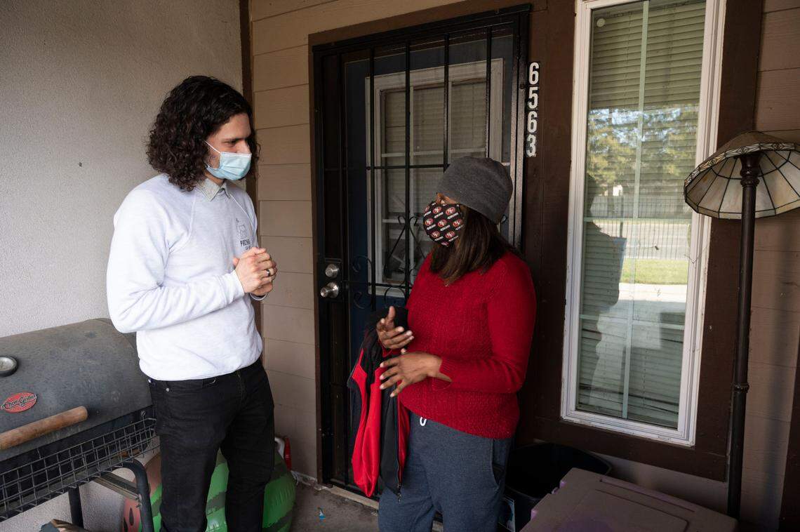 Fienishia Wash talks with Cameron Collins on her front porch in south Sacramento on Saturday. Wash is a recipient of Sacramento’s first direct payment program, where 100 families are given $300 a month. Collins leads the DIPS program through United Way.