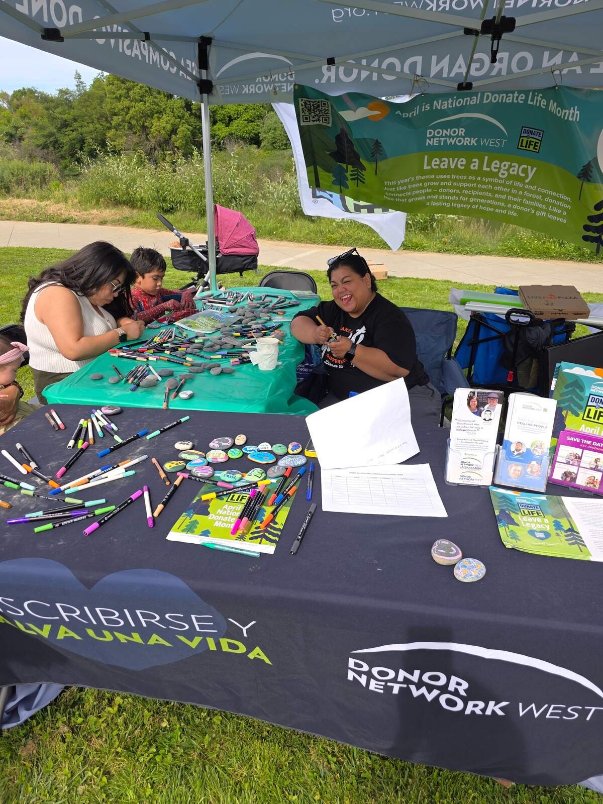 Volunteers for Donor Network West help organize an outreach event during Donate Life Month in April 2026, painting rocks with encouraging messages related to organ donation.