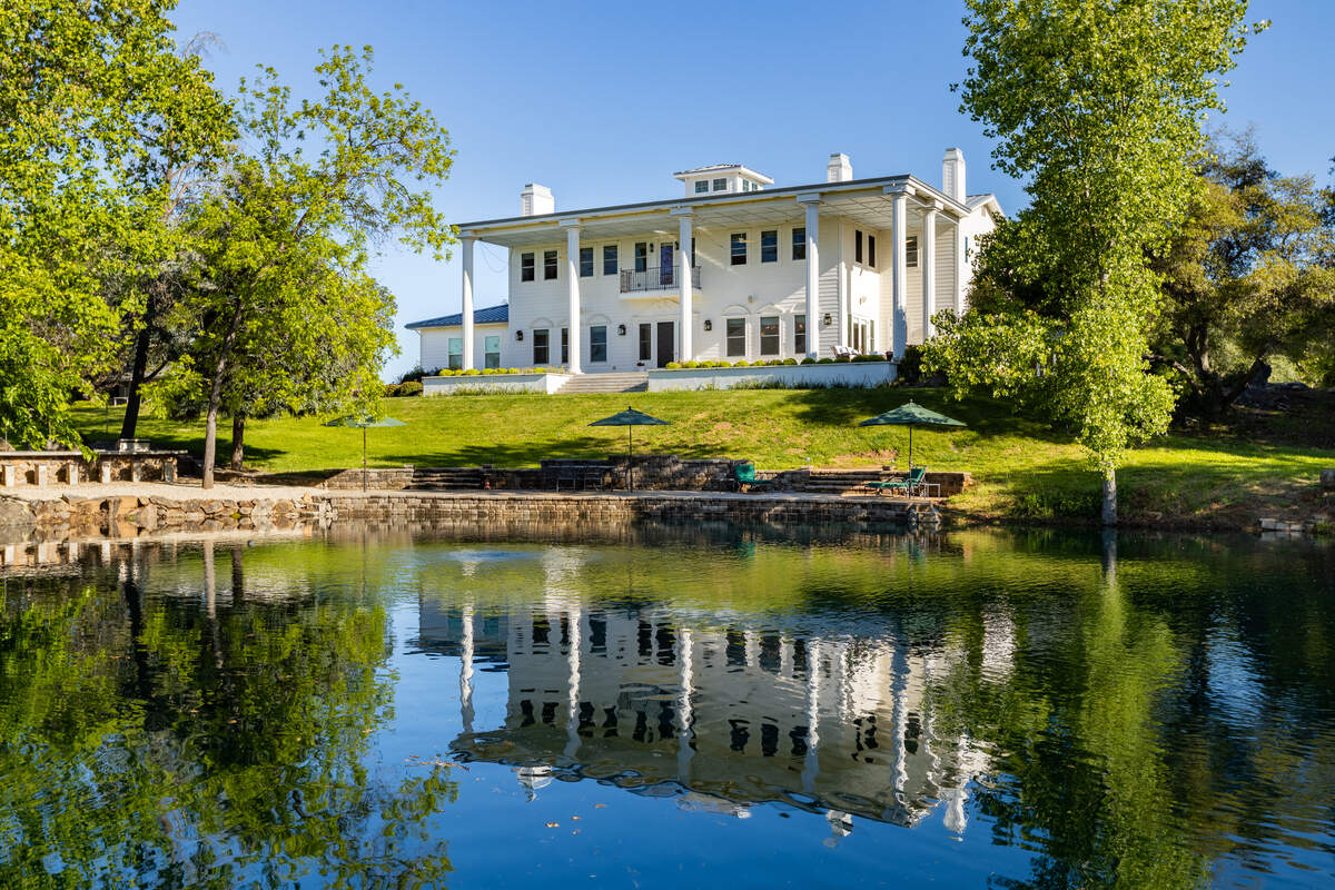 A gated drive curves past a deep pond toward the Mount Vernon-inspired colonial estate at 3100 Newcastle Road in Newcastle, listed for $4.2 million.
