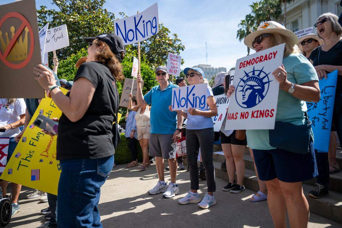 Joseph Cain, left, and Sharron Cain, right, stand on the state Capitol west steps during the “No Kings” protest against the Trump administration in downtown Sacramento on Saturday.