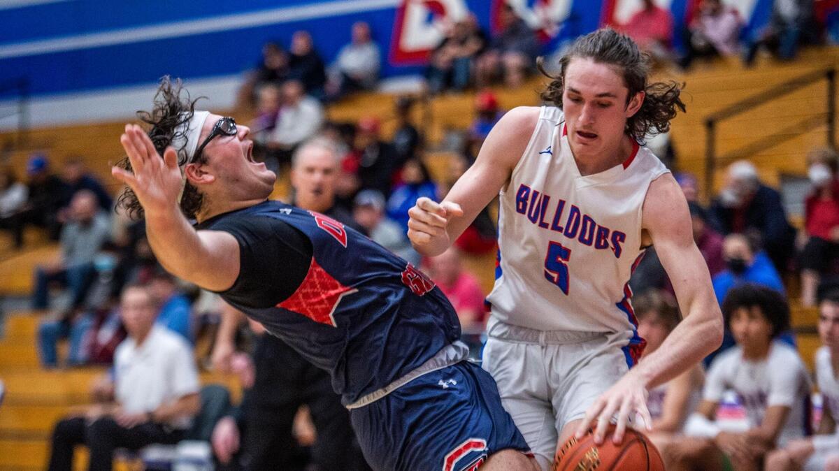 Dublin High School’s T.J. Costello (1) falls back as he defends Folsom High School forward Jake Thoensen (5) under the basket during a boys’ basketball game on Tuesday, March 1, 2022 in Folsom.