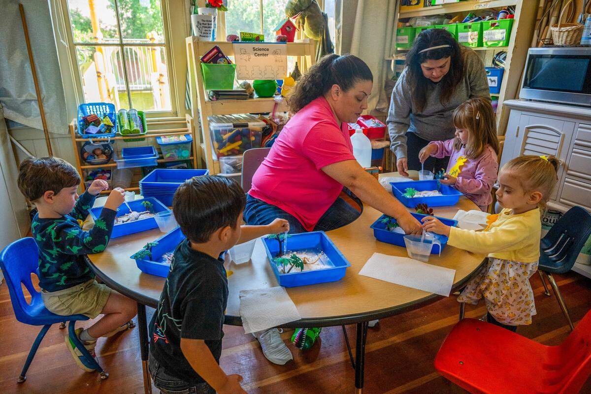 Parents Carrie Arguijo-Barnes, center, and Estrella Carew, right, help with a science project with their daughters and other students at Edward Kelley parent participation preschool in Rosemont on Thursday.
