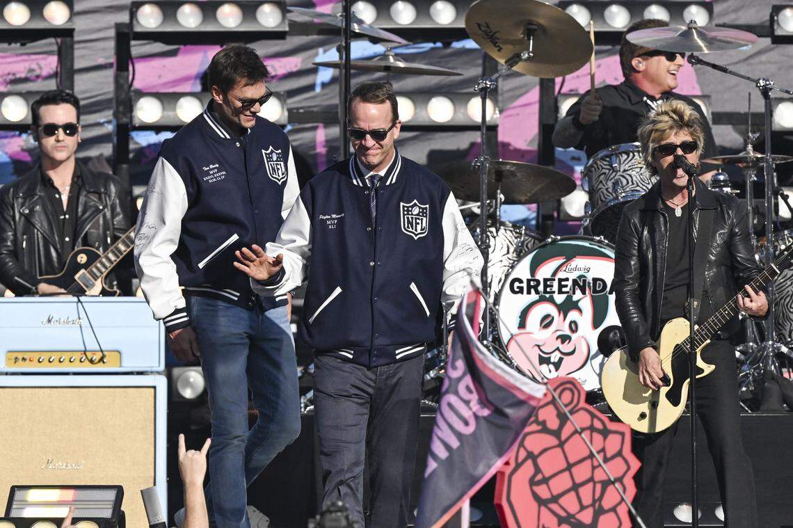 Tom Brady and Peyton Manning stand on stage with Green Day as Green Day performs before the start of Super Bowl LX at Levi’s Stadium in Santa Clara on Sunday, Feb. 8, 2026.