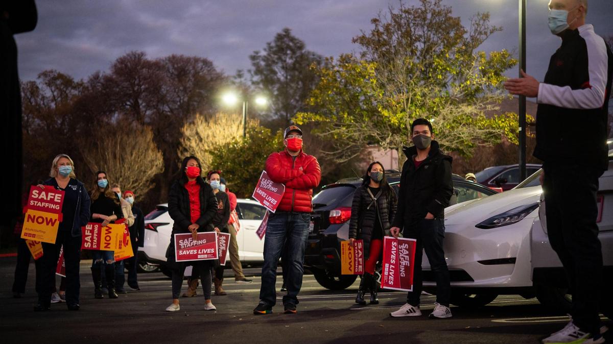 Tom Nacke, center, a registered nurse from Roseville, listens as Shawn Bartlett, labor representative with the California Nurses Association, updates other nurses from Sutter Roseville Medical Center after a car rally Tuesday, Dec. 15, 2020, on the ease of waiving nurse staffing ratio laws after the Newsom administration unveiled an “expedited waiver process” for hospitals.